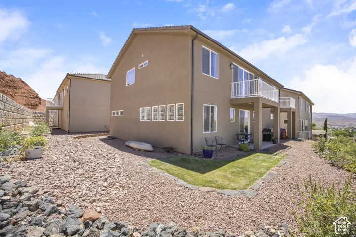 Rear exterior of a multi-level residence featuring a stucco facade and white-framed windows