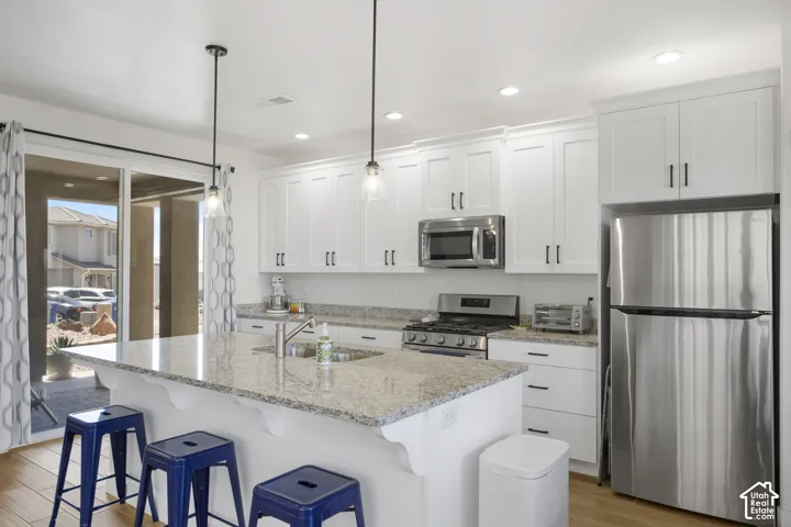 Modern kitchen featuring white cabinetry with dark hardware, stainless steel appliances, and light-toned granite countertops