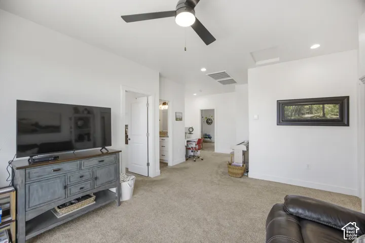 Carpeted living area featuring a ceiling fan with integrated lighting, recessed lighting, and white walls