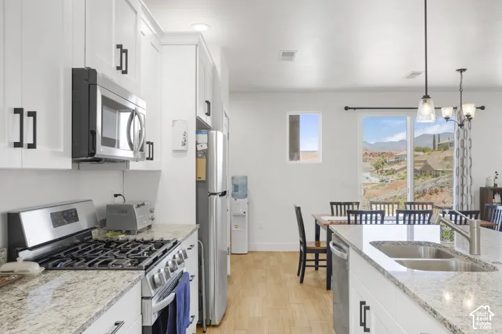 Modern kitchen featuring white shaker cabinetry with black hardware, stainless steel appliances, and light-toned granite countertops