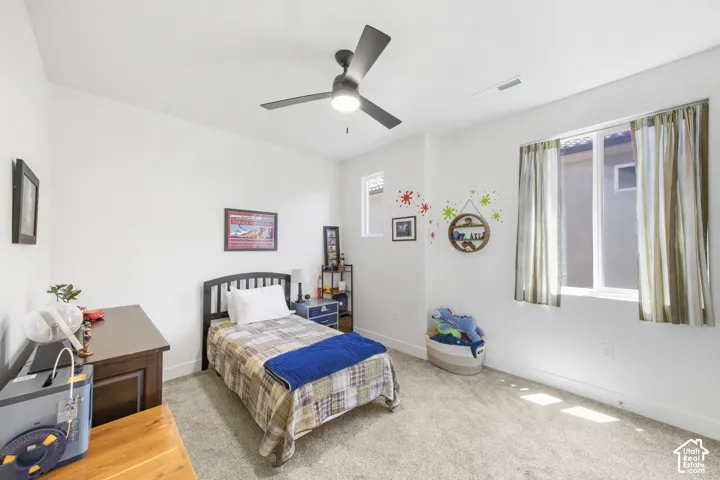 Bedroom featuring neutral carpeting, white walls, and a ceiling fan with integrated lighting