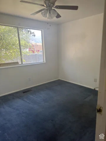 Room featuring a ceiling fan with light fixture, white walls, and blue carpet flooring