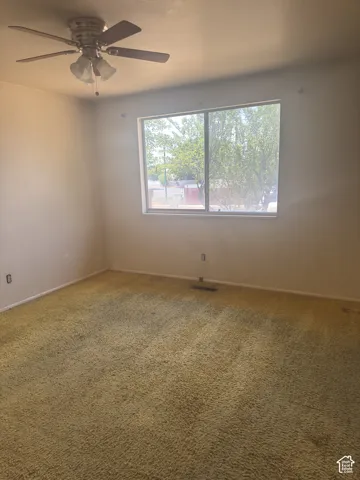 Bedroom with textured carpeting and a ceiling fan light fixture