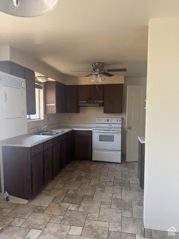 Kitchen featuring dark wood-finish cabinetry, a white countertop, and a double basin sink