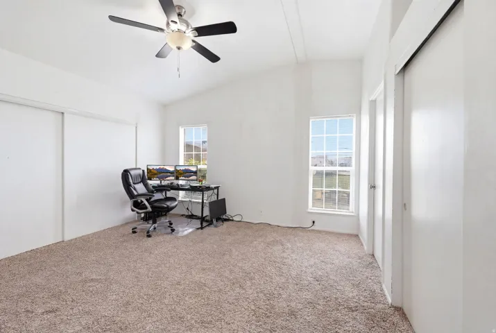 Carpeted interior space featuring an angled ceiling and multiple windows
