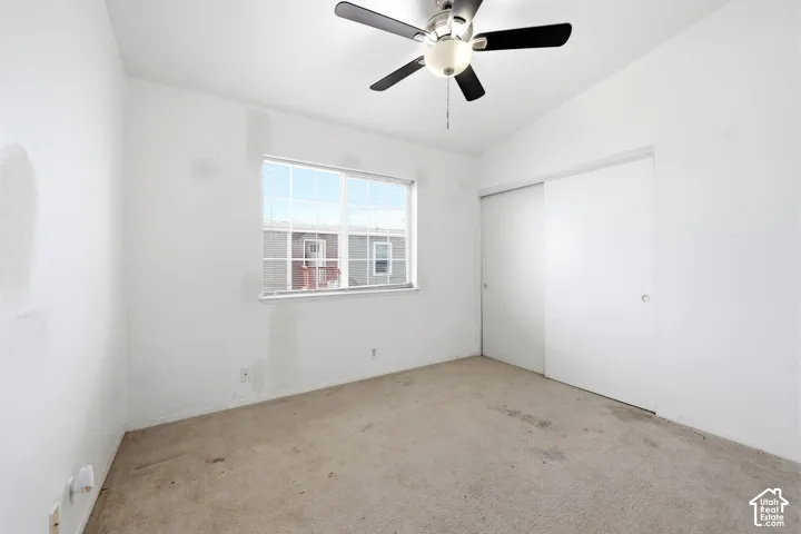 Room featuring a ceiling fan with integrated lighting, a window with white framing, and a sliding closet door