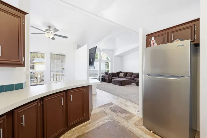 Kitchen featuring wood-finish cabinetry, a built-in stainless steel refrigerator, white countertops, and a green tile backsplash