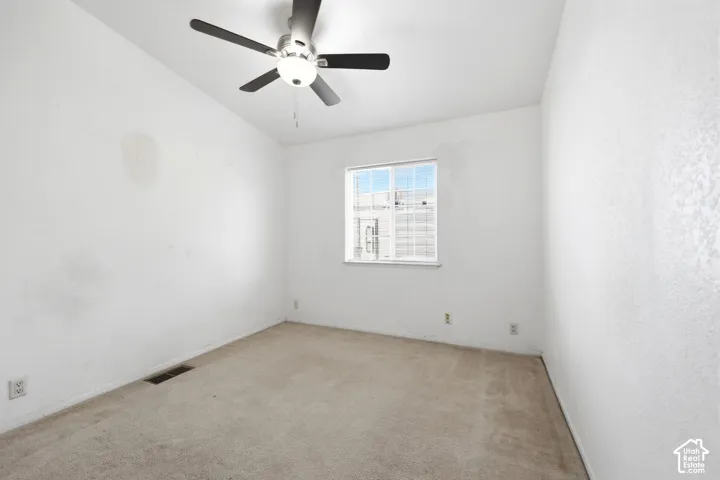 Carpeted room featuring a ceiling fan with integrated lighting, a double-paned window, and white textured walls