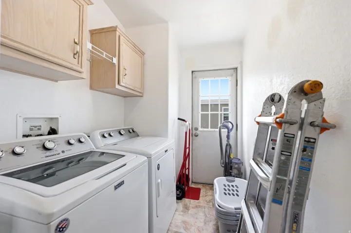Utility room featuring upper cabinetry, a white exterior door with window panes, and patterned flooring