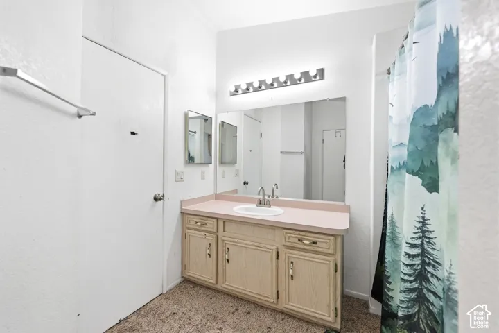Bathroom featuring a single vanity with an integrated sink, broad wall mirror, and overhead strip lighting