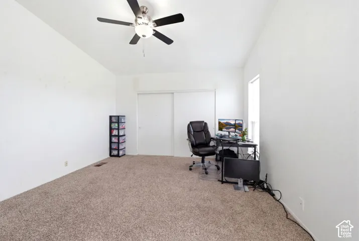 Carpeted room featuring a ceiling fan with integrated lighting, a window providing natural light, and a built-in closet with sliding doors