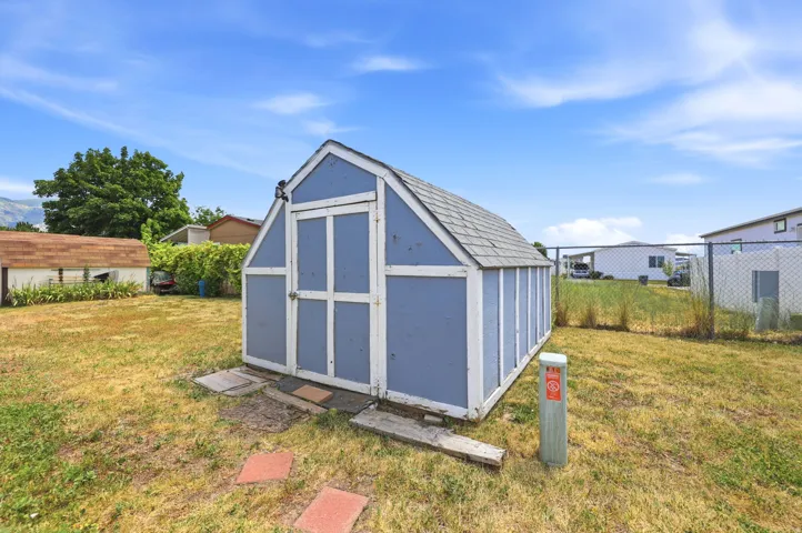 Blue painted storage shed with a gabled roof and light gray shingles