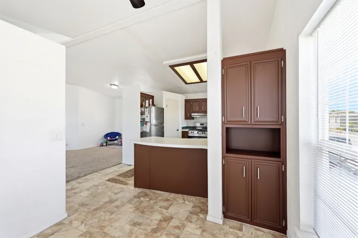 Kitchen with brown cabinetry and light-colored countertops, featuring a built-in pantry cabinet and tiled flooring