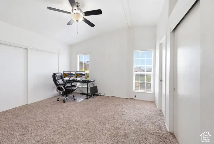 Carpeted interior space featuring an angled ceiling and multiple windows