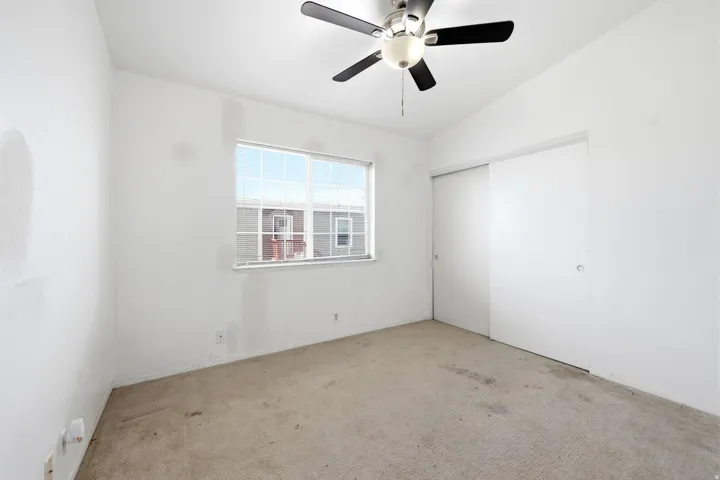 Room featuring a ceiling fan with integrated lighting, a window with white framing, and a sliding closet door