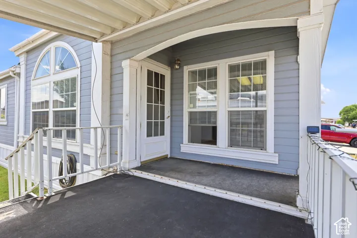 Covered front porch entry with light blue siding, white railings, and a glass-paneled front door