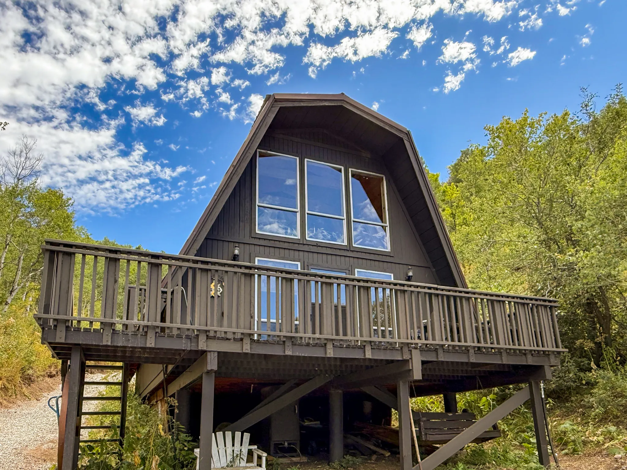 A-frame residence featuring a large elevated deck, multiple windows, and a dark exterior finish