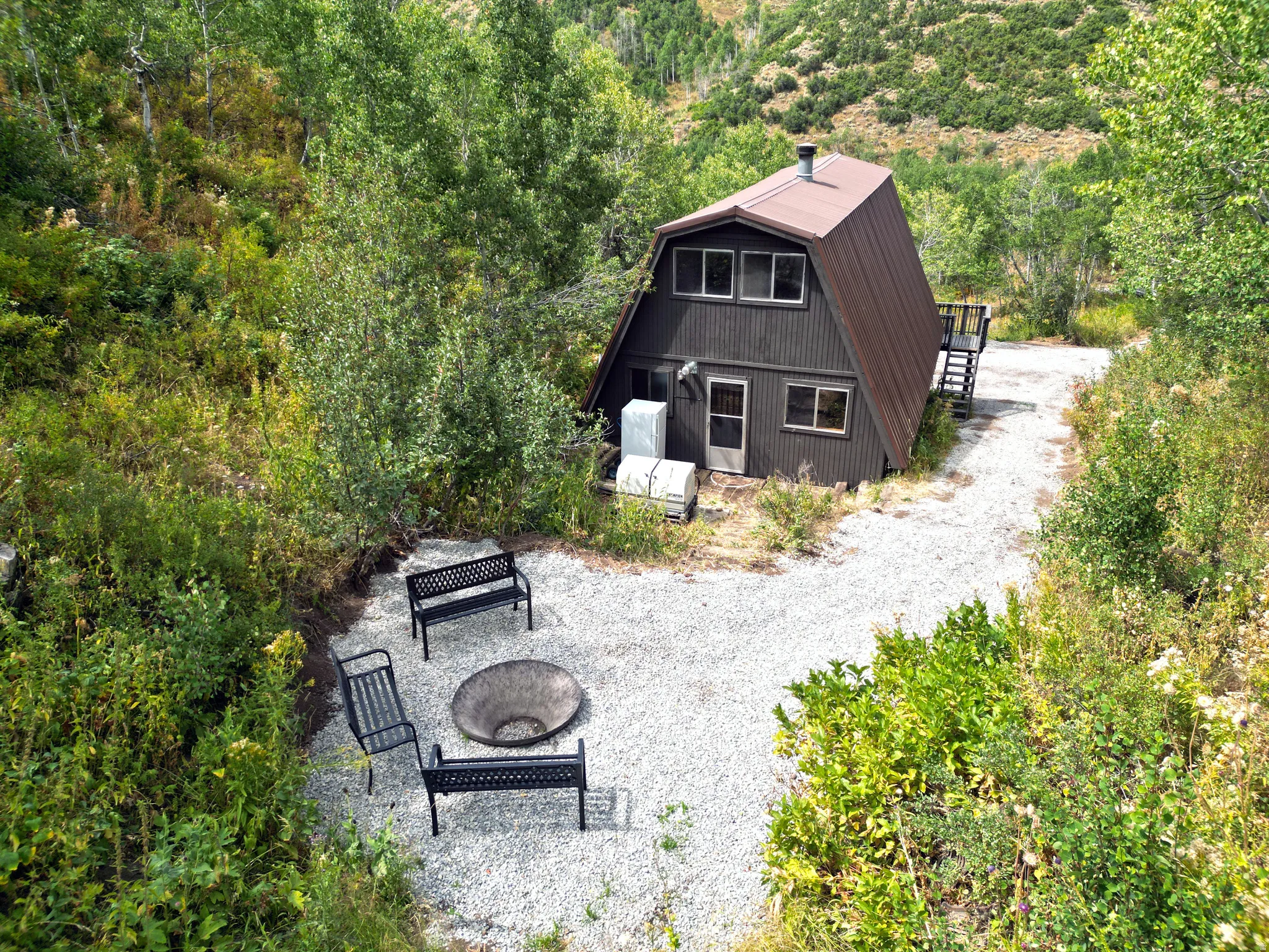 A-frame residence with dark siding, a brown metal roof, and surrounding natural landscaping