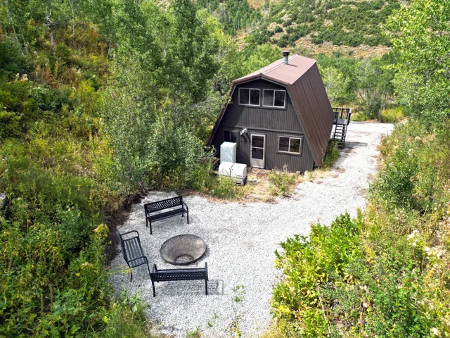 A-frame residence with dark siding, a brown metal roof, and surrounding natural landscaping