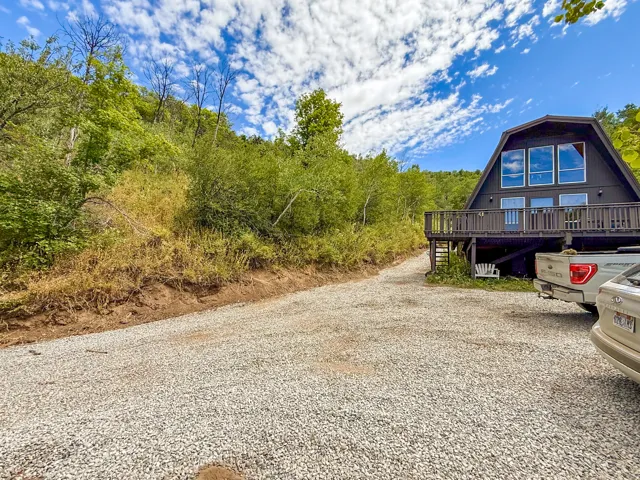 A-frame exterior with dark siding and a prominent gravel driveway