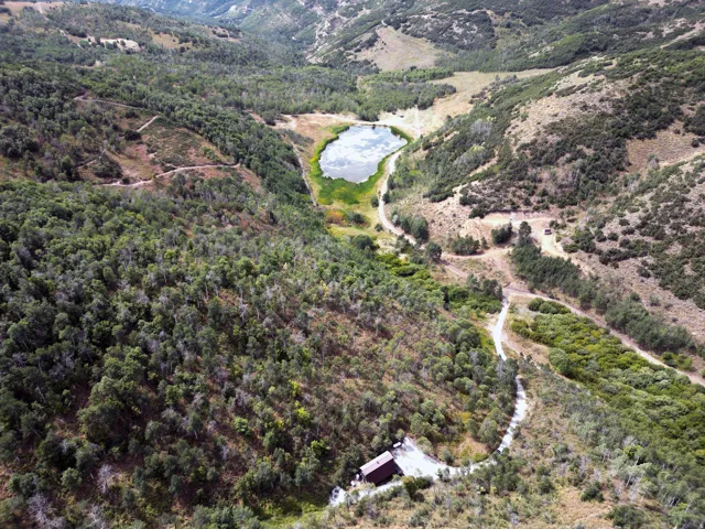 Aerial landscape featuring extensive wooded terrain, a central body of water, and a single structure