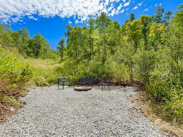 Gravel outdoor area featuring a built-in fire pit surrounded by seating and natural landscaping