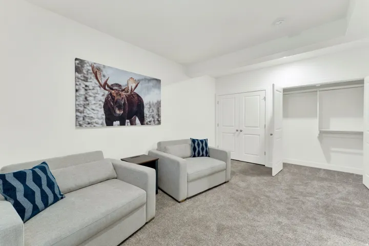 Carpeted room featuring white walls, a built-in closet with bi-fold doors, and an additional set of double panel doors