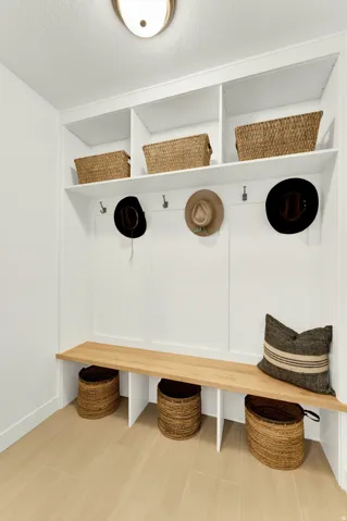 Built-in white storage unit featuring a light wood-finish bench, upper open shelving, and lower storage cubbies