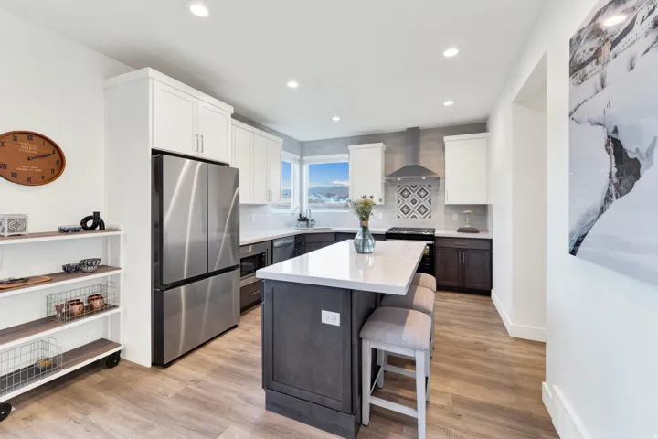 Modern kitchen featuring a central island with a light-toned countertop, stainless steel appliances, and a decorative tile backsplash