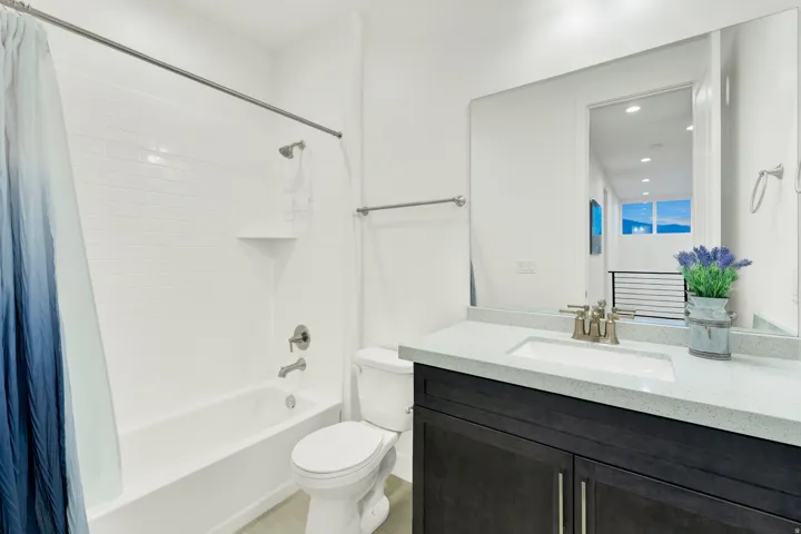 Bathroom featuring a dark wood-finish vanity with a light speckled countertop and undermount sink