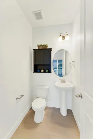 Powder room featuring a white pedestal sink, wood-finish flooring, and an oval mirror