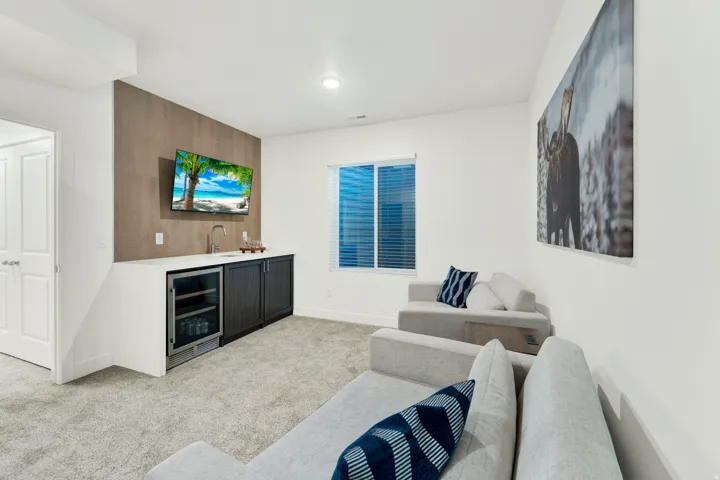 Entertainment space featuring a built-in wet bar with a stainless steel beverage refrigerator, sink, and dark cabinetry