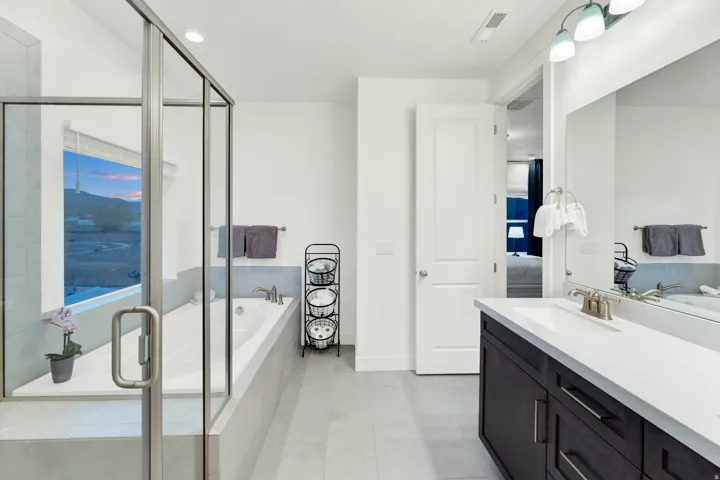 Spacious bathroom featuring a built-in soaking tub, walk-in shower with glass enclosure, white vanity with integrated sink, brushed nickel fixtures, and light-toned tile flooring