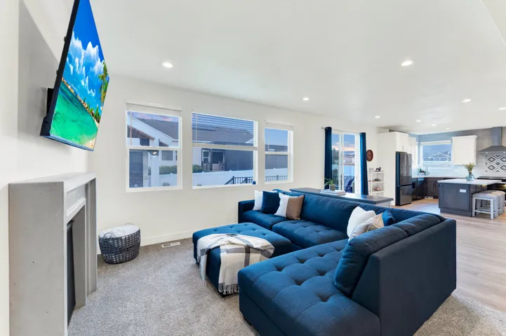 Open-concept living space featuring recessed lighting, a stone-finish fireplace, and multiple windows with blinds