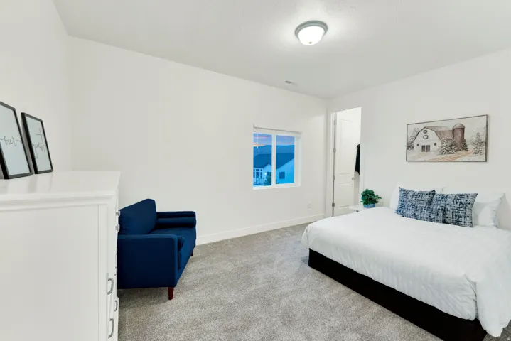 Bright interior room featuring a window with exterior visibility, light grey carpeting, white baseboards, and a semi-flush mount ceiling light fixture