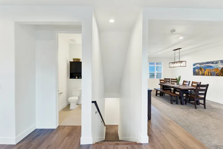 Open dining area featuring wood-finish flooring transitioning to carpet, a multi-light linear chandelier, and ample natural light from a multi-pane window