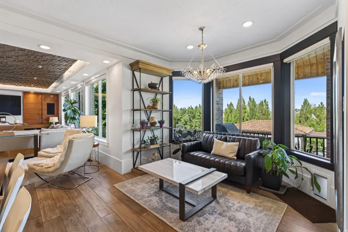 Living area featuring large bay windows, wood-finish flooring, recessed lighting, and a decorative ceiling panel