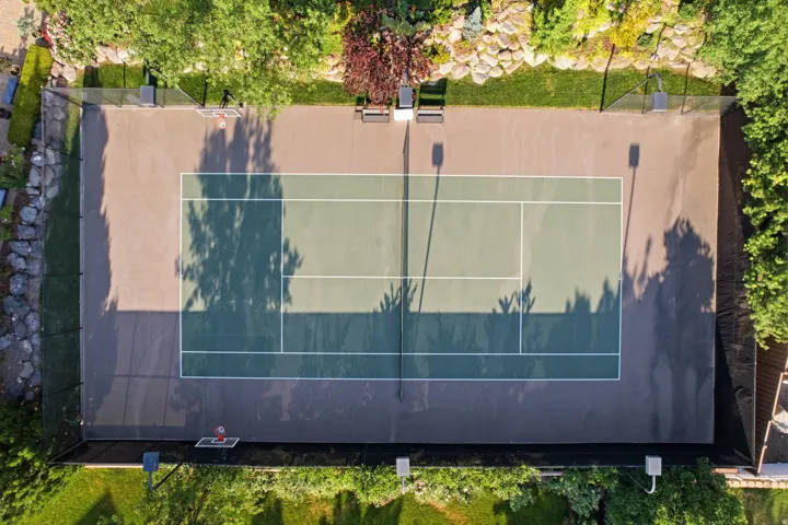Multi-sport court featuring a tennis court with two-tone green surfacing and white lines