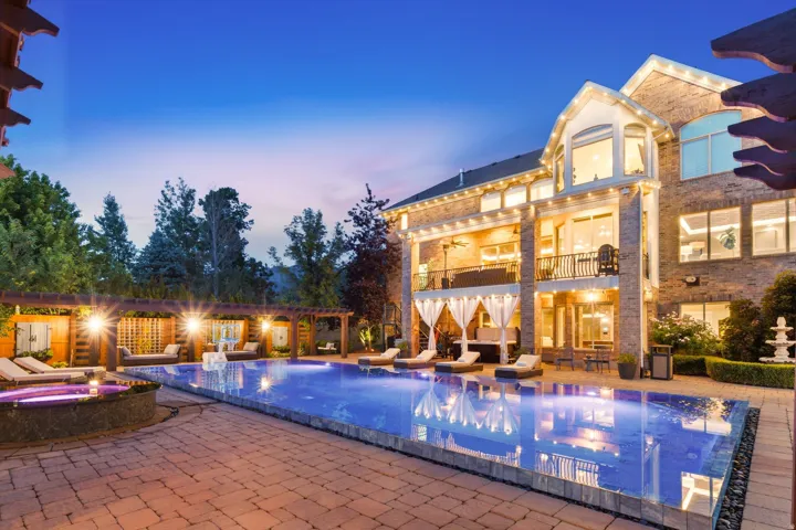 Expansive backyard featuring a large swimming pool, integrated spa, and extensive paver patio