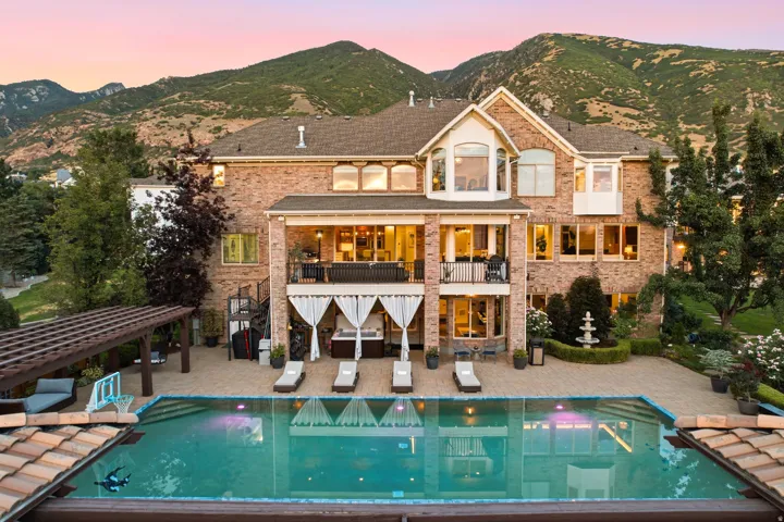 Brick exterior residence with a multi-level patio, an outdoor swimming pool, and a pergola