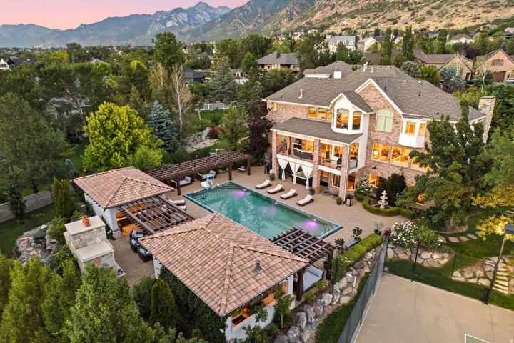 Expansive brick residence with a large swimming pool, two covered cabanas, and a tennis court