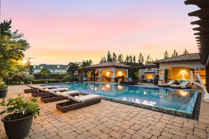 Expansive paver patio surrounding a rectangular swimming pool with integrated spa