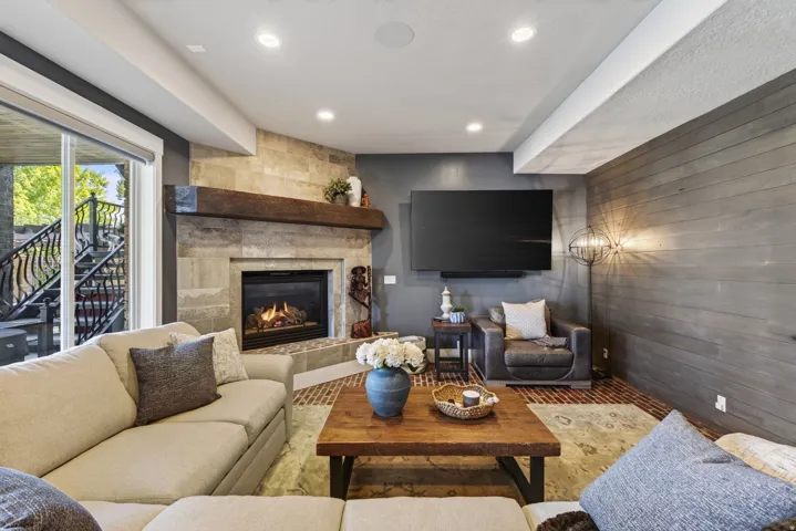 Stone-clad fireplace with a substantial wood mantel, integrated fireplace insert, and brick-patterned hearth