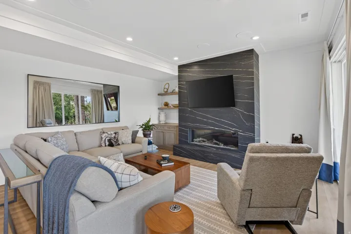 Guest House Living area featuring a floor-to-ceiling fireplace with black stone surround, wide plank wood-finish flooring, recessed lighting, and crown molding