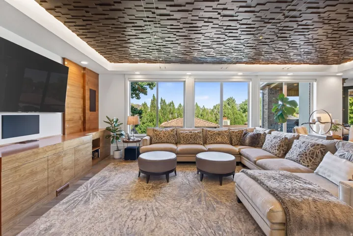 Living room featuring a coffered ceiling with recessed lighting, a custom built-in entertainment center, and expansive windows