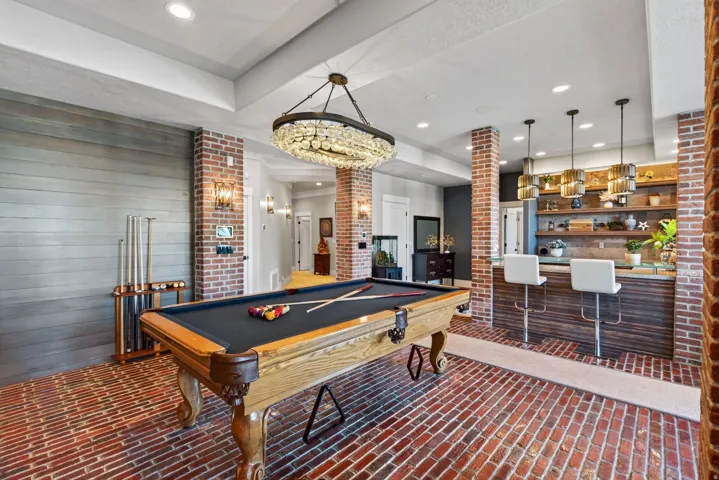 Entertainment room featuring brick flooring, a built-in bar with wood-finish paneling, and a pool table