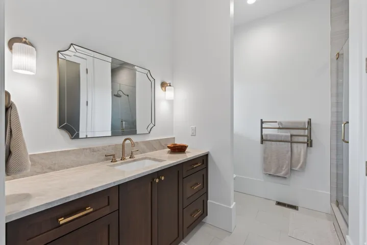 Guest House Bathroom featuring a dark wood vanity with gold-tone hardware, a light-toned countertop, and a framed mirror