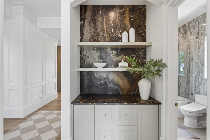 Guest House Built-in cabinetry with stone countertop and backsplash, featuring integrated shelving and an arched alcove