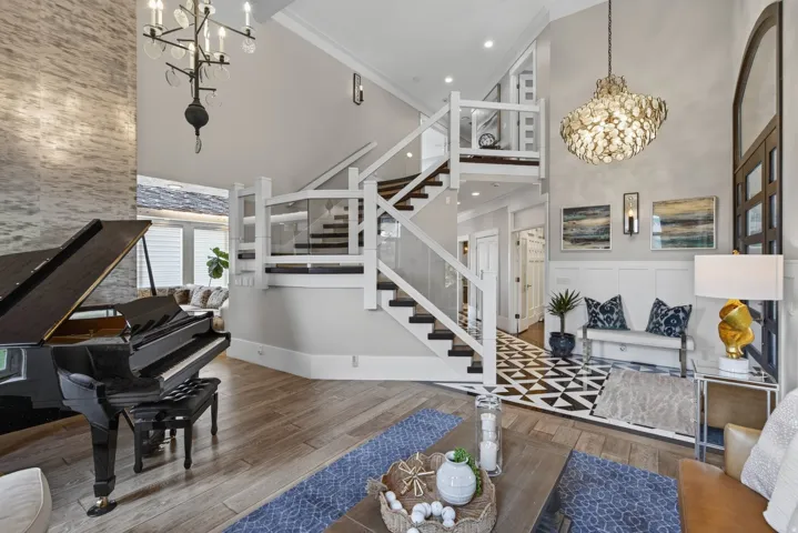 Grand entry featuring a dramatic two-story staircase with glass panel railing and dark wood treads