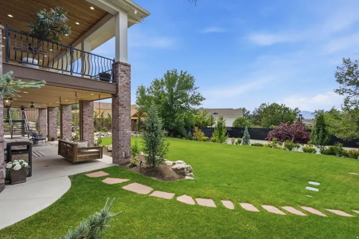 Guest House Expansive backyard featuring a manicured lawn, stone pathway, and mature landscaping